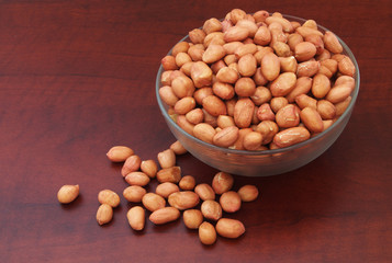Peanuts on wooden table in glass bowl