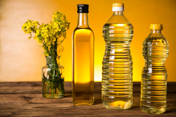 Rapeseed flowers and rapeseed oil in a bottle on the table