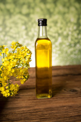 Rapeseed flowers and rapeseed oil in a bottle on the table