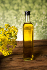 Rapeseed flowers and rapeseed oil in a bottle on the table