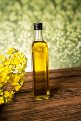 Rapeseed flowers and rapeseed oil in a bottle on the table