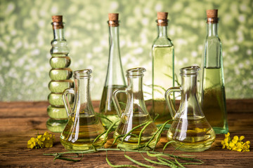 Seeds and rape flowers in bottles and carafes with rapeseed oil