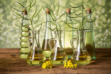 Seeds and rape flowers in bottles and carafes with rapeseed oil