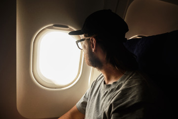The young man looks out the window of the plane