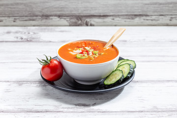 Gazpacho. Traditional Spanish tomato soup with fresh tomatoes, fresh cucumber, on white wood base
