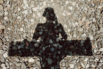 Female shadow on the stones with a board behind