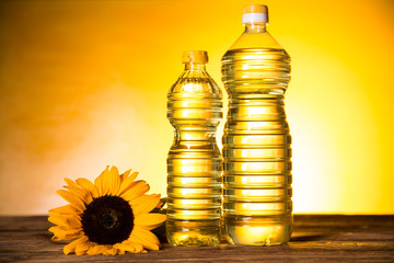 Sunflower oil in a bottle, sunflower flower on a wooden table