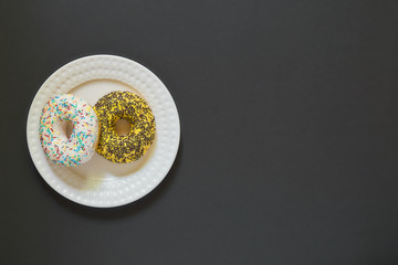 Glazed vanila donut on a plate on black stone background. Minimal flat lay with copy space                      