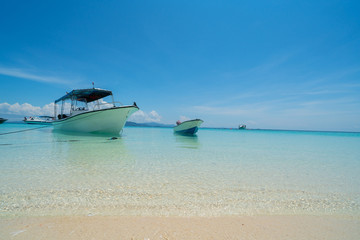 White coral sand beach with moored line-up of boats used to bring tourists to island with moored line-up of boats used to bring tourists to island