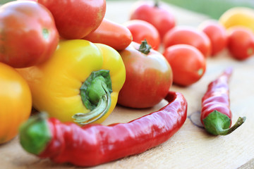 Mix of hot red peppers, fragrant yellow paprika and ripe tomatoes, on a wooden table.