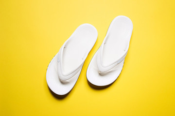 Flip flops on a yellow isolated background. White female flip flops.