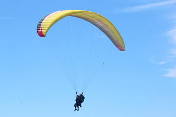 Tandem paraglider flying yellow wing
