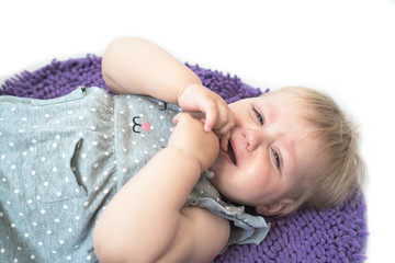 Little kid crying lying on floor. Little cute girl in gray dress is capricious lying on the floor....