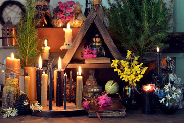 Fototapeta na wymiar Burning candles, flowers and crystal gem stones on witch table.