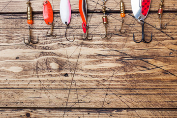 Fishing hooks and baits in a set for catching different fish on a wooden background with copy space. Flat lay