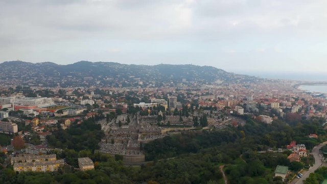 Aerial, tilt down, drone shot, over La Croix des gardes park, towards the Cimetiere du grand jas graveyard
in the city of Cannes, on a cloudy day, in the French Riviera, in France