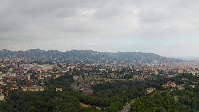 Aerial, rising, drone shot, over La Croix des gardes park, overlooking the Cimetiere du grand jas graveyard
and buildings in the city of Cannes, on a cloudy day, in the French Riviera, in France