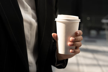 Close up of side view of a woman holding coffee cup in hands