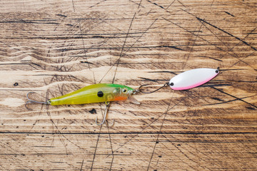 Fishing hooks and baits in a set for catching different fish on a wooden background with copy...