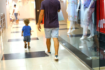 dad and son walk through the mall view from the back
