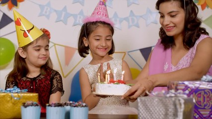 Birthday Celebration at Indian Family - Caring mother brings the cake with candles for her daughter . Fun party for Birthday at home -  A cute little girl celebrating it with her mother and sister