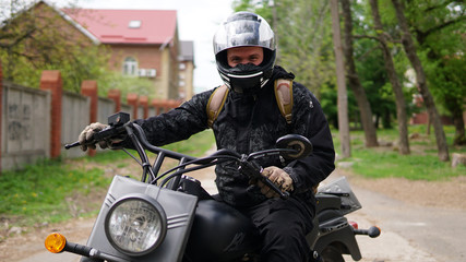 Fototapeta na wymiar Smiling Biker man in a helmet sitting on his motorcycle