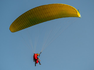 Paraglider with passanger flying in the blue sky.