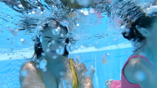 two young woman underwater together smiling and swimming. Slow motion. 12,5%, 200fps