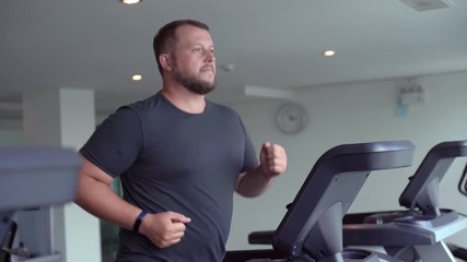 full male runs on a treadmill in a gym. concept of weight loss and sport. side view.