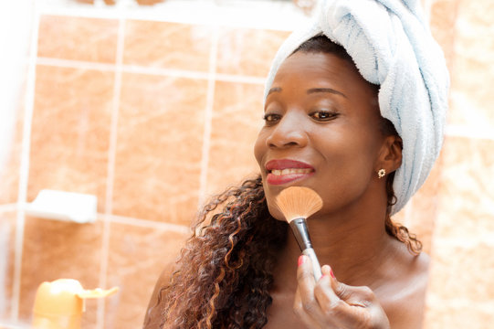 young woman applying face powder in the mirror in the bathroom.