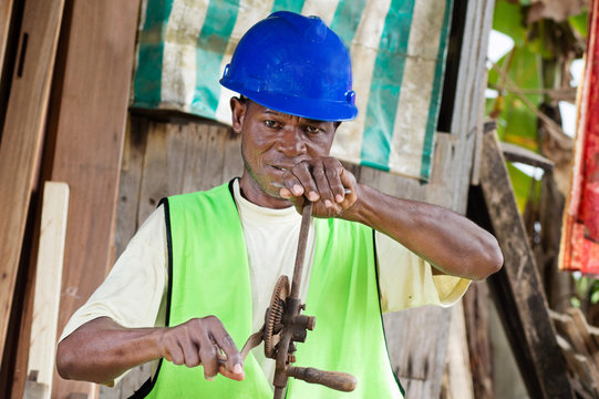 The carpenter in his workshop made with wood, is now turning a crank.