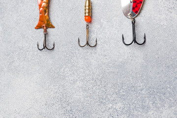 Fishing hooks and baits in a set for catching different fish on a grey background with copy space....