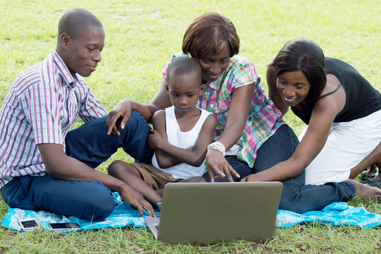 A group of friends and a child looking at a laptop screen.