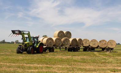 tractor pulling long trailer with bales of hay © Levtrona
