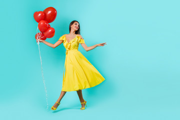 fashionable girl posing in a yellow fashionable dress with a belt on a blue background.  girl with balloons. - Image. 