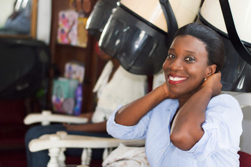 smiling young woman sitting at the hair salon is in the process of arranging her hair.
