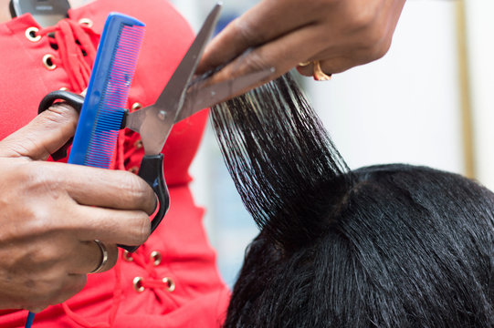 The hairdresser arranges the hair of her client by cutting them with scissors.