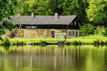 Fototapeta na wymiar Old timbered barn by lake with metal bridge