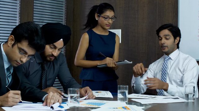 Indian manager having a meeting with his young employees in the conference room - Corporate Concept. Young employees discussing an important matter with their boss in their office room