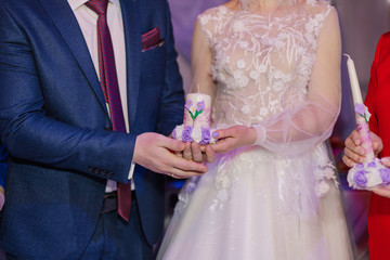 Candle in the hands of the newlyweds symbolizes hearth and well-being of the family.