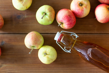 fruit drinks and season concept - glass bottle of apple juice, cider or vinegar on wooden table