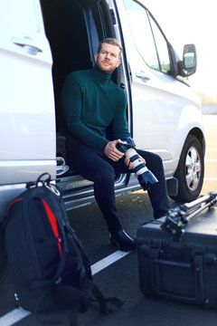 Professional photographer outside. Sit down in his van