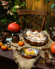 Autumn outdoor still life with pumpkin cinnamon buns in oval glass dish on wooden table