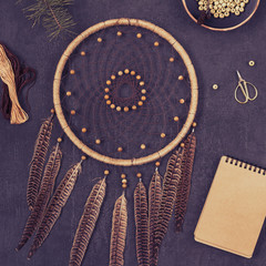 Creative workplace. Dreamcatcher, thread, scissors, and wooden beads, a notebook. Flat lay. Top view. Copy space