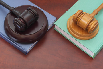 Two judge gavels and legal books on wooden table