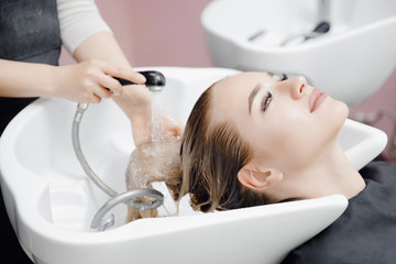 Beautiful blond woman getting hair wash in beauty salon