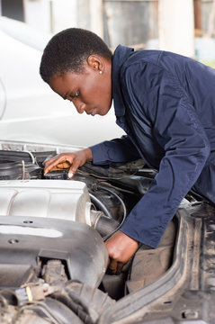 Young female mechanic repairs a car by putting the engine in good condition.