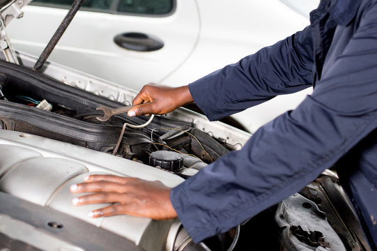 Closeup  of a hand holding a key on the engine of a broken car.