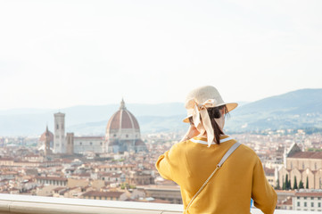 Young woman looking at the city of Florence from the viewpoint. Back view. Empty space for text