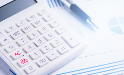 White calculator and report with chart and graph, concept of annual financial profit overview, banking and investment, copy space, macro, close up
